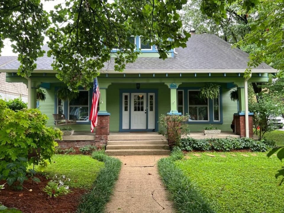 The iconic green craftsman exterior with American flag and manicured landscaping makes a charming impression.