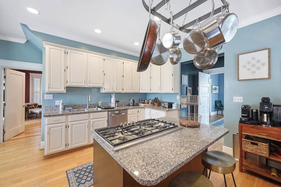 The open kitchen with white cabinets and stainless appliances flows into the main living area.