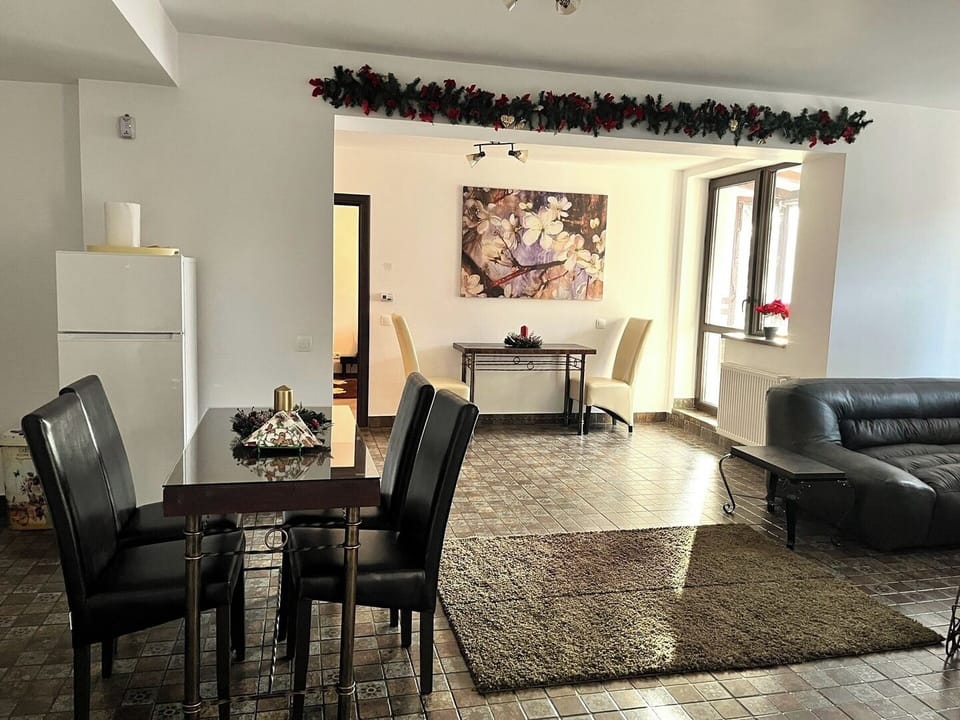 Elegant and well-appointed entryway featuring an ample dining table, artwork, and a vase of fresh flowers, setting a warm and welcoming tone as guests arrive - your favorite accommodation in the heart of Sinaia