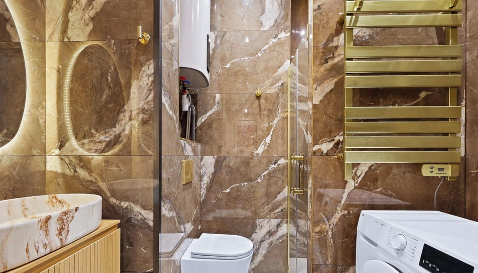 Salle d’eau élégante avec baignoire vasque, WC séparés et lave-linge.