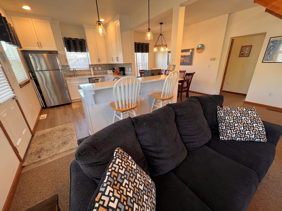 Relax in this stylish loft space where contemporary comfort meets modern design, featuring a cozy sectional and sleek kitchen below.