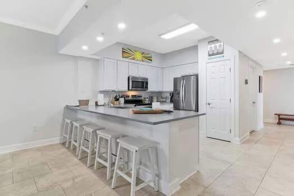 Fully stocked kitchen at Harbour Point 301 with high-quality cookware, modern appliances, and barstool seating—perfect for families who love to cook during their Perdido Key vacation.