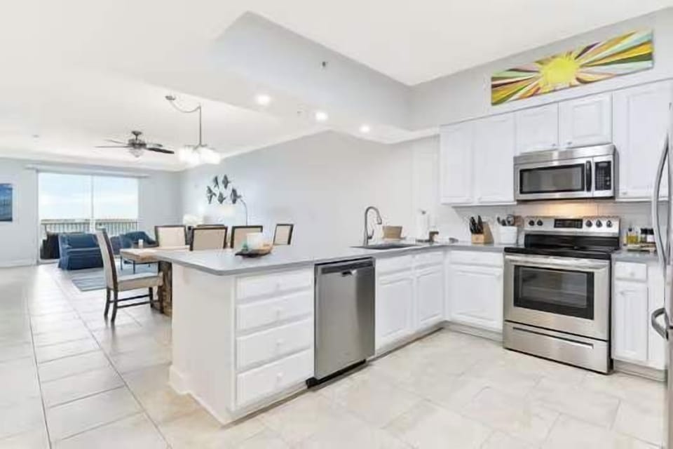 Fully stocked kitchen at Harbour Pointe 301, perfect for families who love to cook, featuring modern appliances, ample counter space, and barstool seating for casual dining during your Perdido Key vacation.