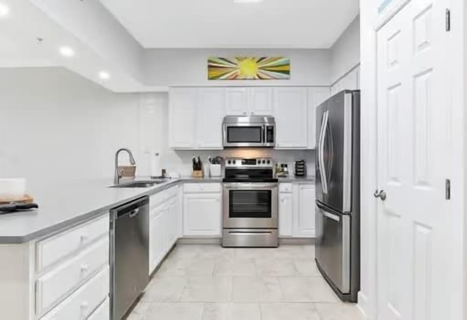 Fully stocked kitchen at Harbour Pointe 301, perfect for families who love to cook, featuring modern appliances, ample counter space, and barstool seating for casual dining during your Perdido Key vacation.
