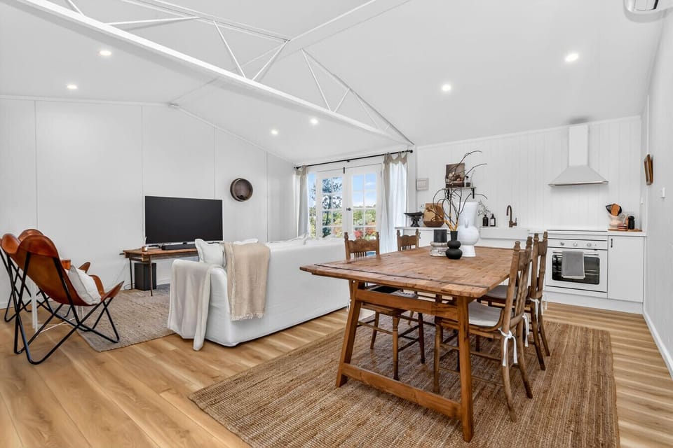 Light-filled living, dining, and kitchen space with high ceilings.