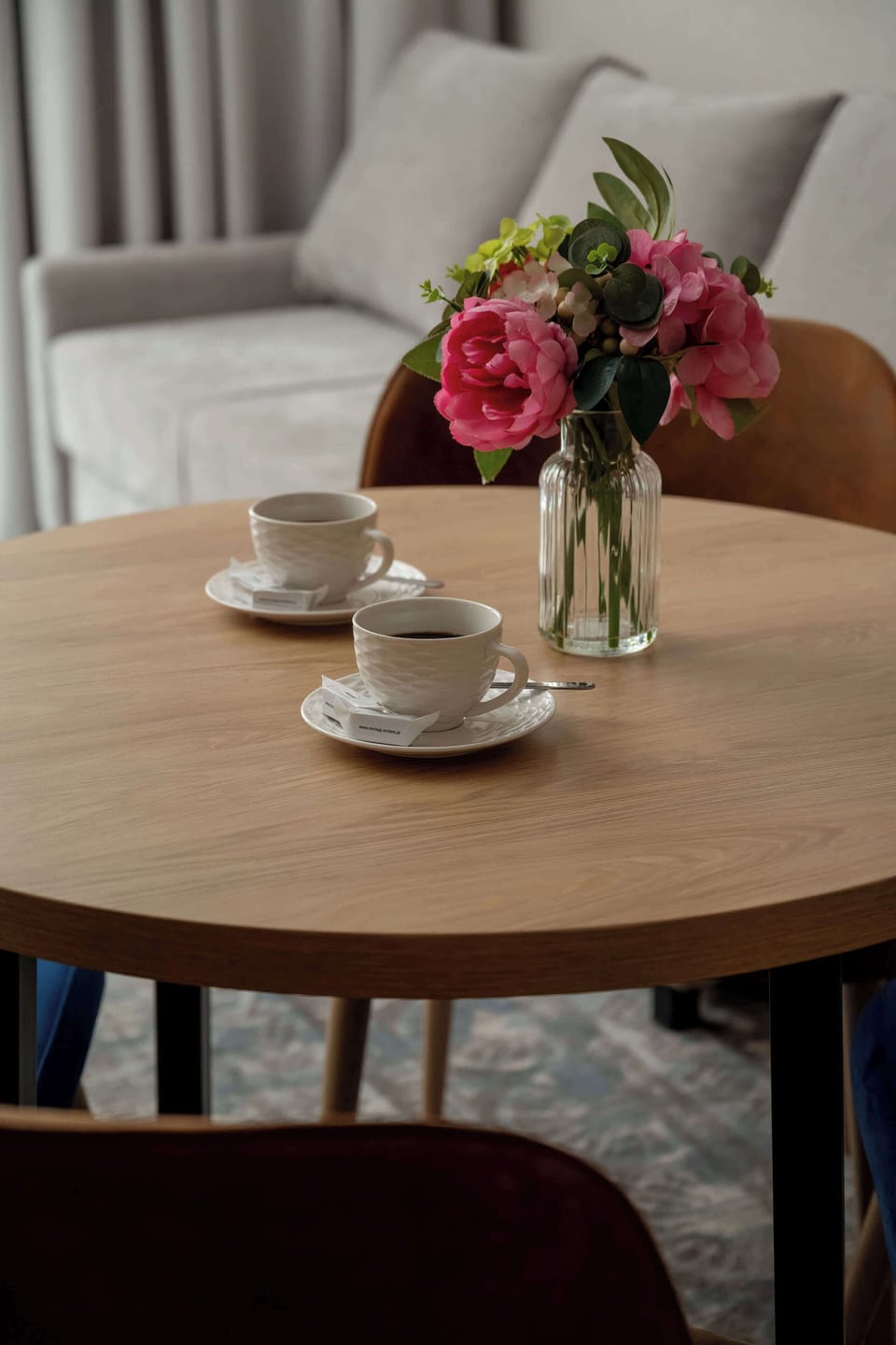 A decorative table setup with flowers in a bright interior space. It adds a cozy and welcoming touch.