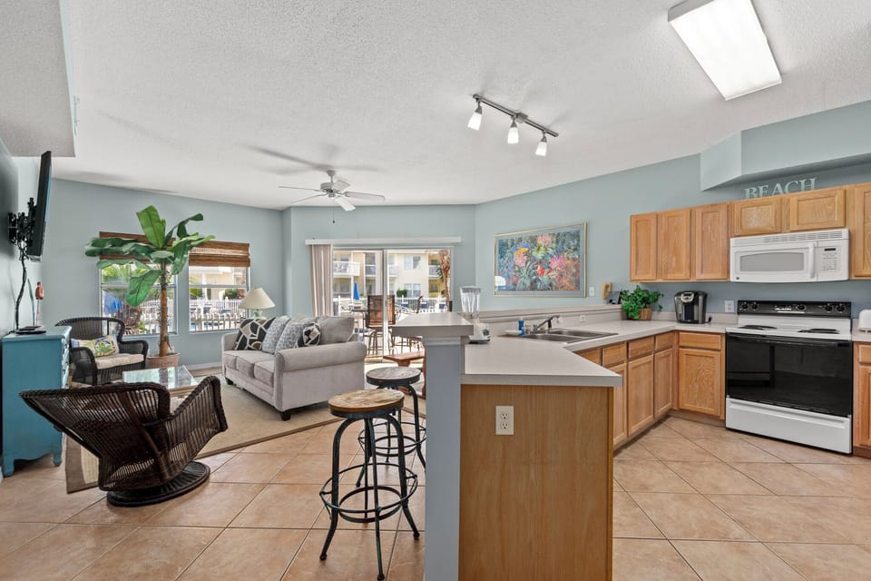 Your spacious open-concept living awaits, where coastal blue walls meet warm wood accents and natural light floods through the skylight above.