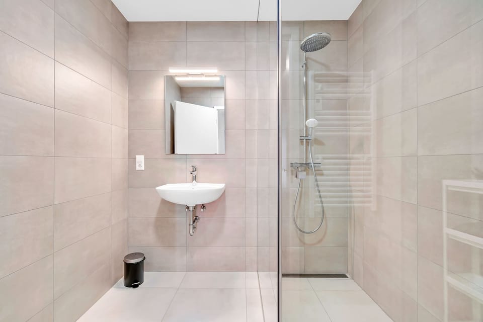 Spacious bathroom with glass shower and essential amenities for a comfortable stay.