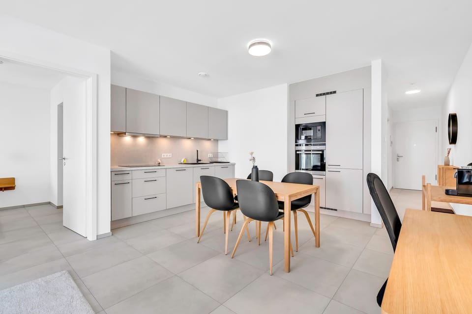 Open layout with dining table and kitchen, offering a functional and social space.