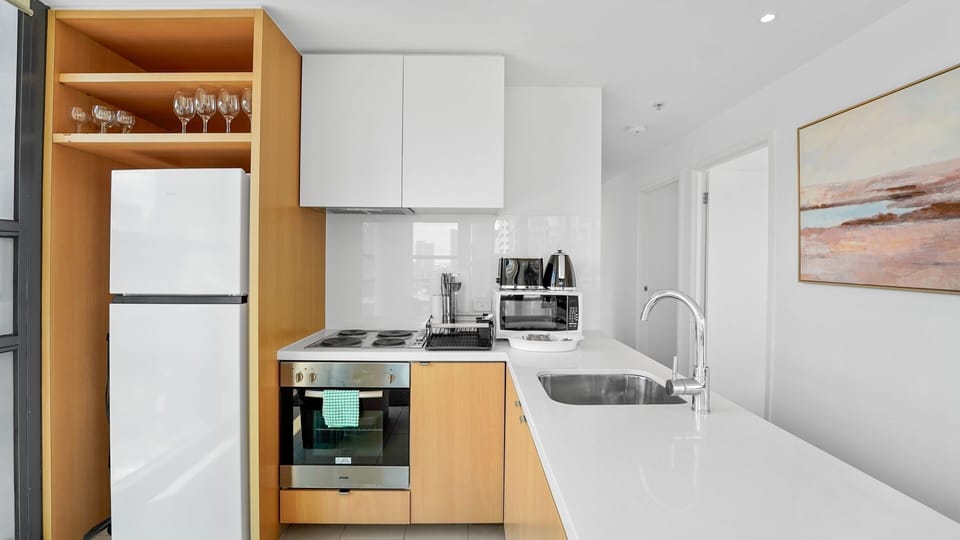 Compact kitchen with fridge, oven, cooktop, microwave, and all the basics for home cooking.