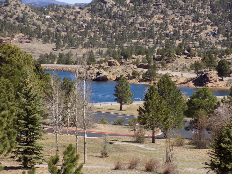 A serene mountain landscape with view of Mary's Lake, winding road, and scattered pine trees set aga