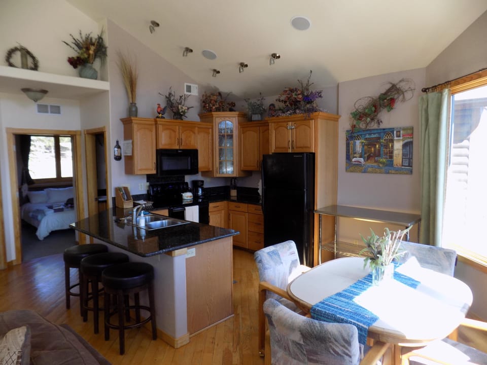 A spacious, sunlit living area flows into a cozy kitchen and dining space, featuring vaulted ceiling