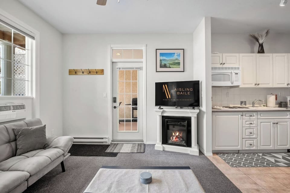 Living room with an electric fireplace, Smart TV, walkout access to the ground-floor patio, and cozy seating options with a double-sized sleeper sofa (all linens provided.)