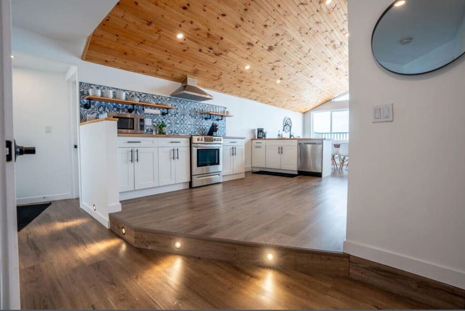 Open-Concept Design: The kitchen flows seamlessly into a dining area with vaulted wood ceilings, perfect for hosting family dinners.  Panoramic Windows: Prepare meals while enjoying floor-to-ceiling views of the sparkling lake waters.