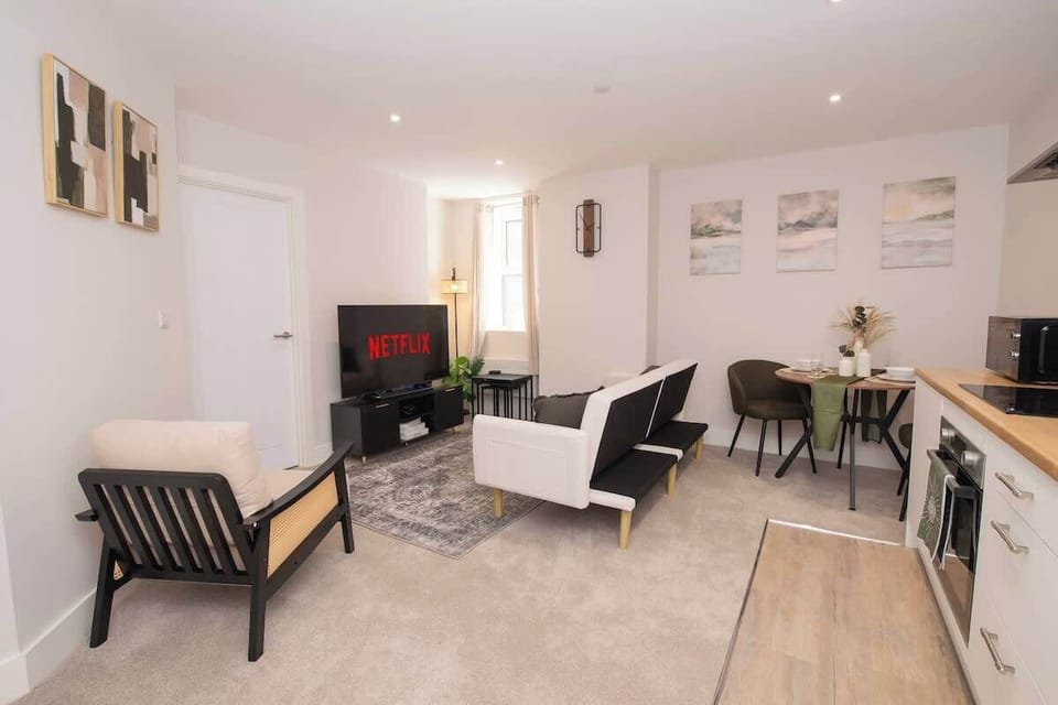 Unwind in our cozy living room featuring a smart TV for movie nights, with a spacious open-plan layout that flows seamlessly into the kitchen and dining area.