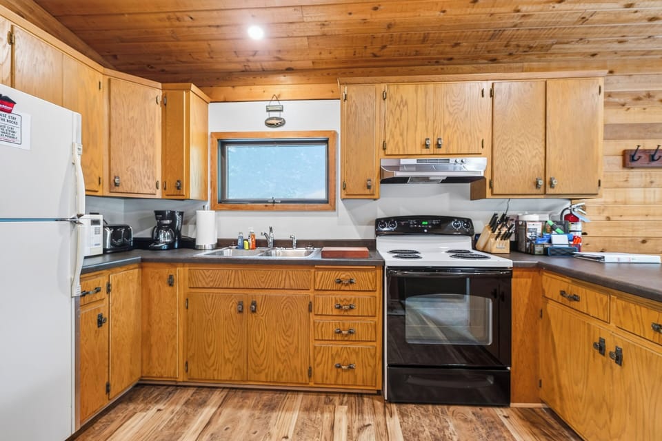 Wood cabinets with a white refrigerator and a white and black stove.