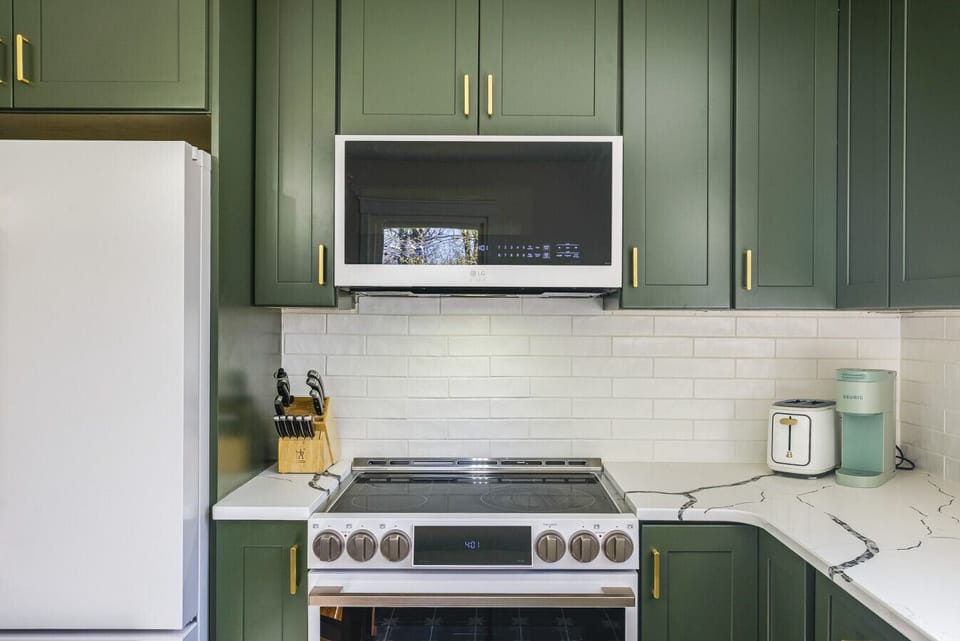 Kitchen featuring modern white and gold appliances, a high-end electric range, and a Keurig coffee maker for your morning brew.