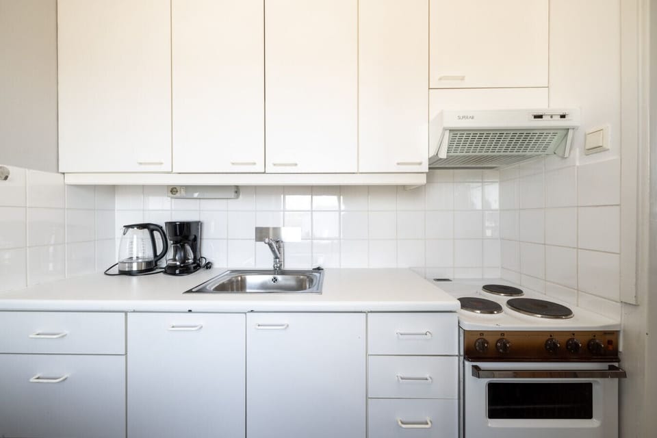 A clean, white kitchen with ample cabinet space and essential appliances.