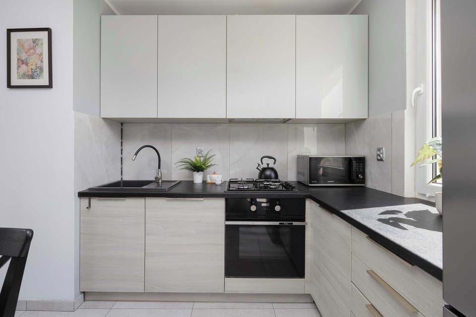 A modern kitchen with white cabinetry and built-in appliances. The design is functional and uncluttered, ideal for cooking.