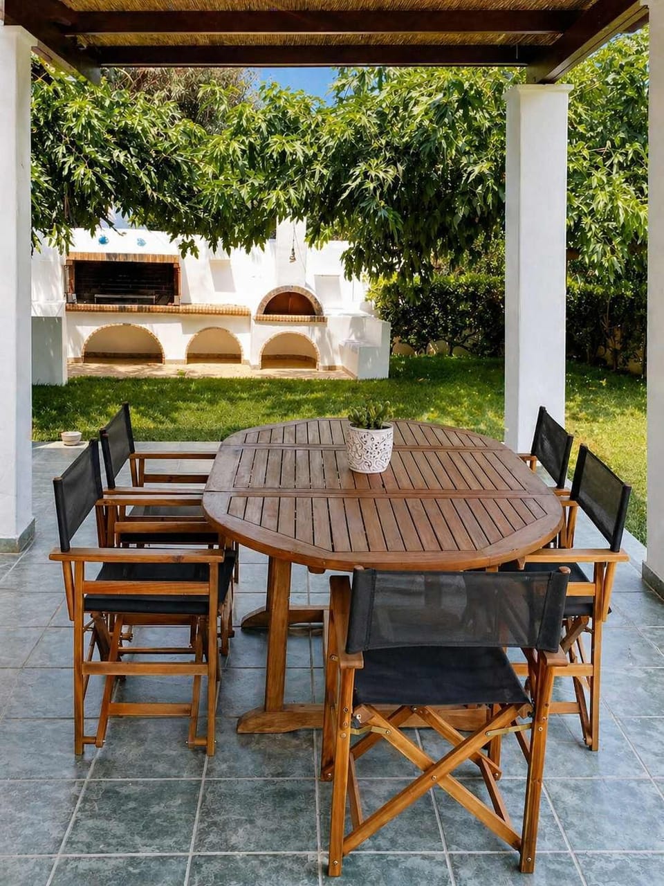 Outdoor dining area on the ground floor with traditional BBQ and garden.