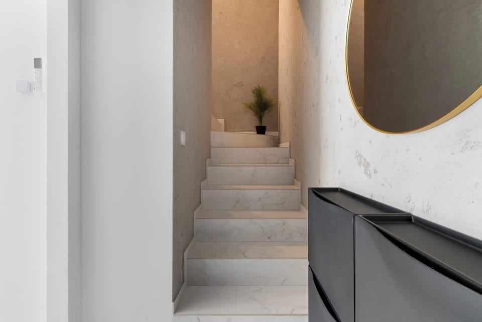A narrow hallway with a staircase leading upward and modern lighting accents.