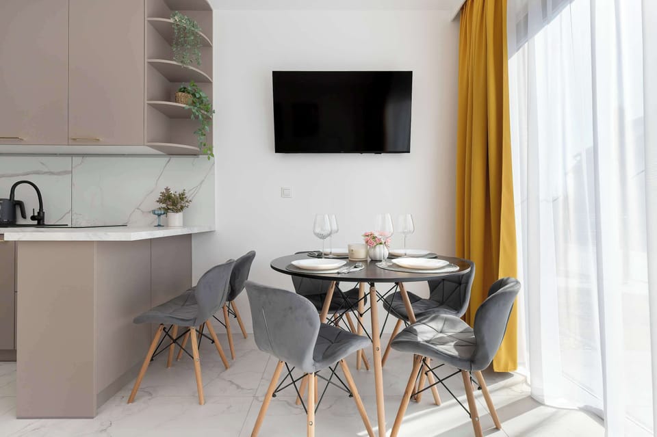 A dining setup beside a kitchenette, featuring modern chairs and warm accent curtains.