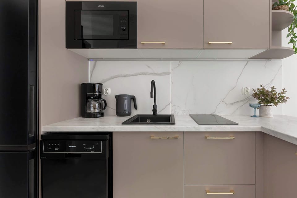 A compact kitchen area with sleek cabinets, a stove, and countertop appliances arranged neatly.