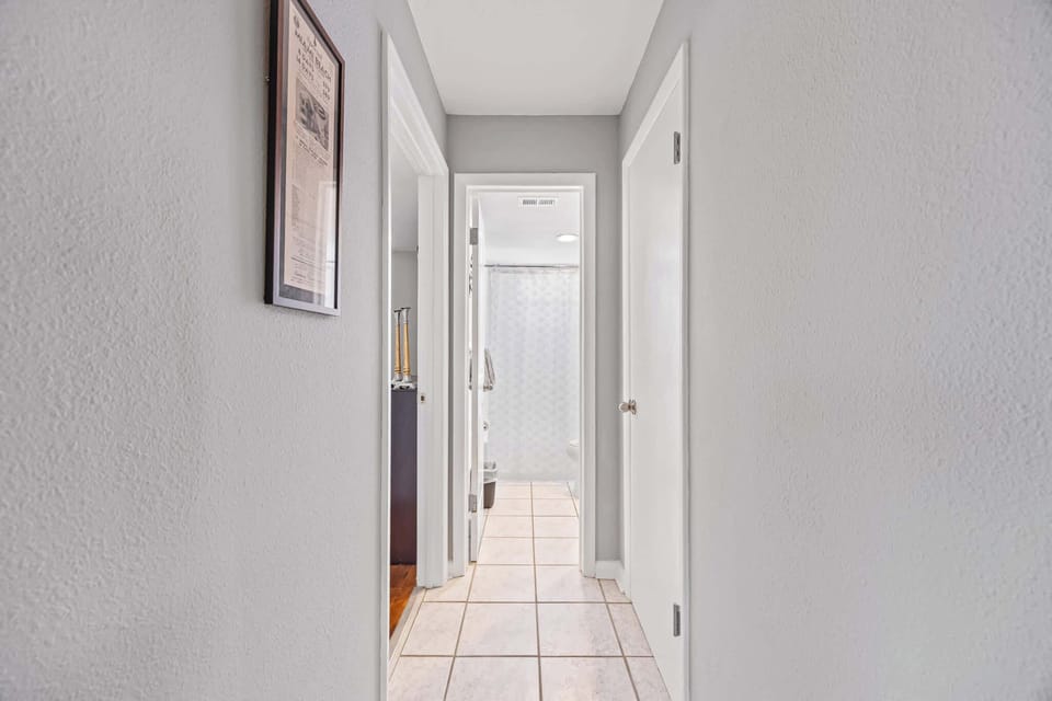 Hallway with tiled floor leading to a bathroom with a shower curtain.