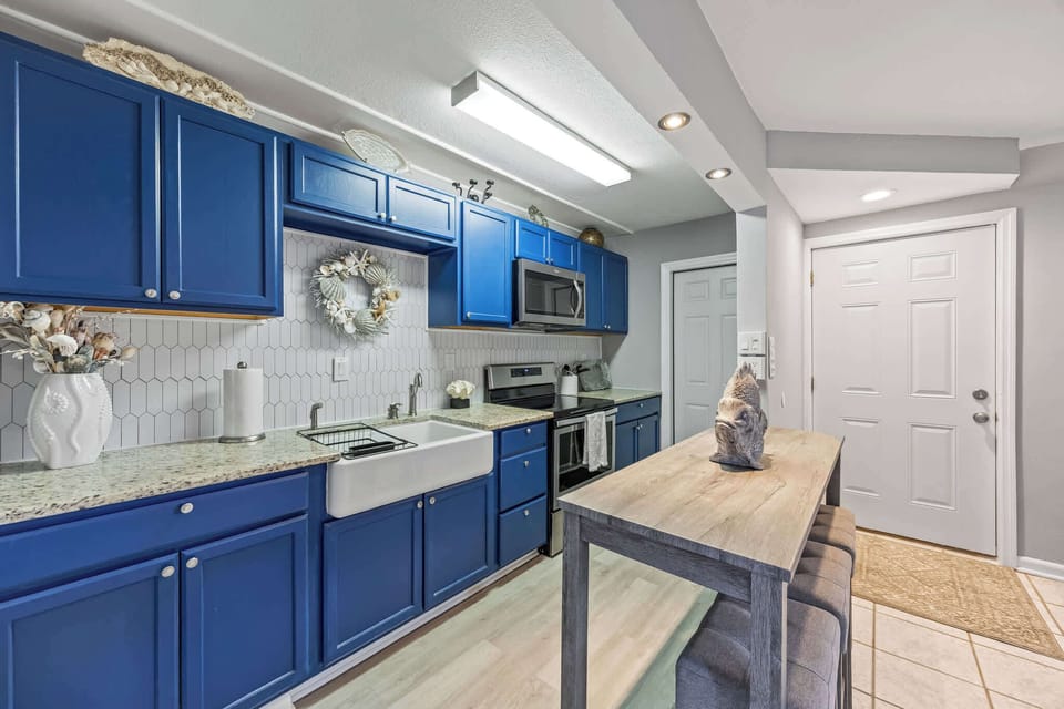 Kitchen with blue cabinetry, farmhouse sink, and a wooden island for casual dining.