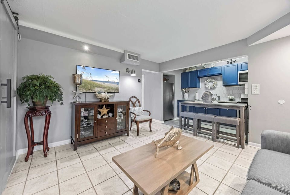 Open living area with coastal decor and a kitchen featuring blue cabinetry and a breakfast bar.