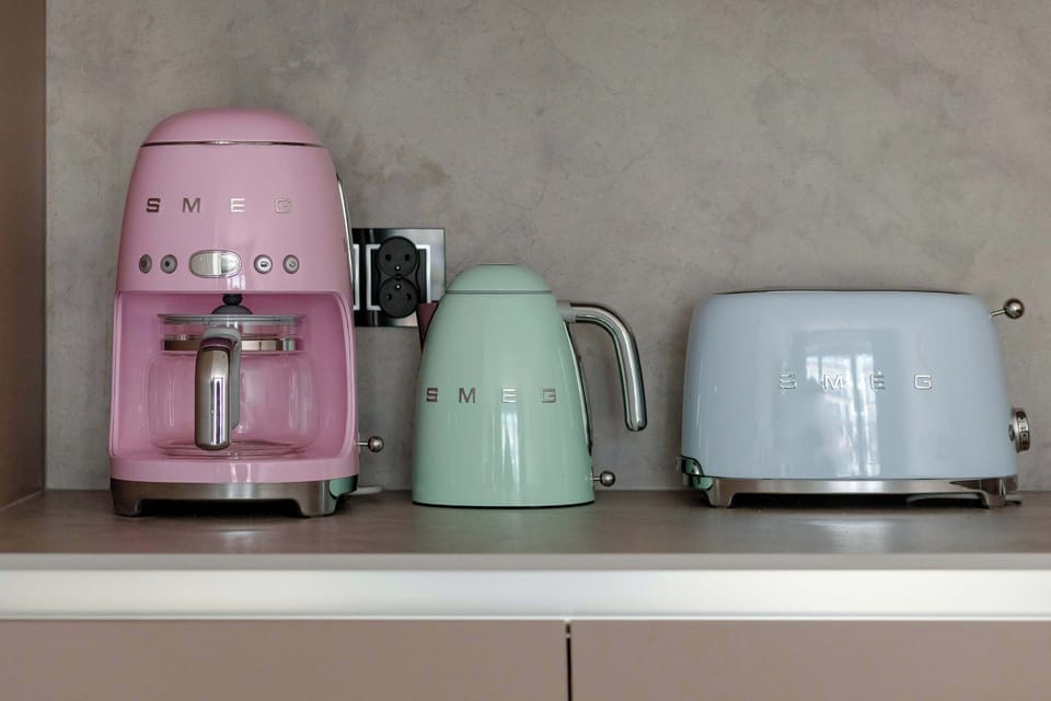 A shelf displaying colorful small kitchen appliances like a toaster and kettle.