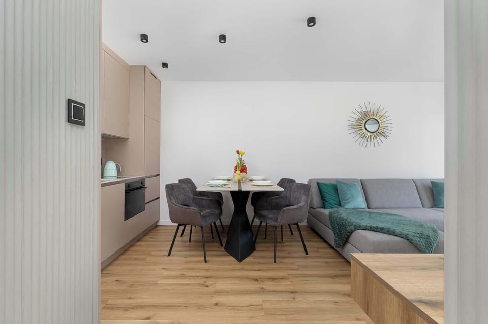 A stylish dining nook with a round table, upholstered chairs, and a decorative wall accent.