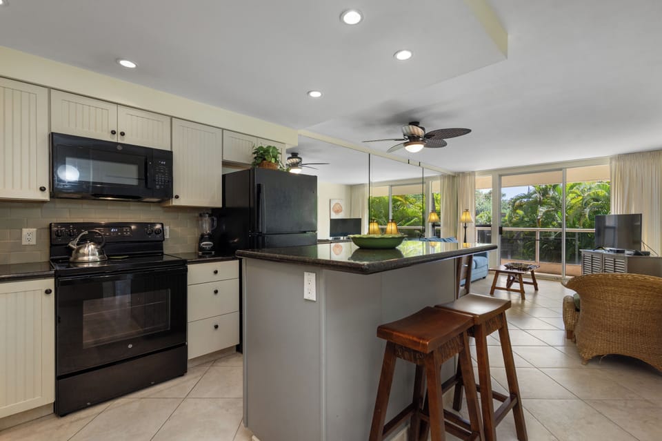 Your fully equipped kitchen awaits with modern appliances and a convenient breakfast bar overlooking the tropical living space.