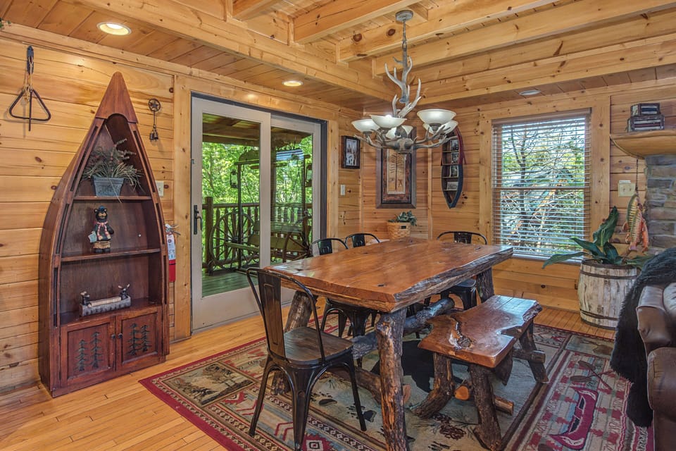 Gather around your rustic dining table under the antler chandelier, where warm wood surrounds you and forest views invite memorable meals.