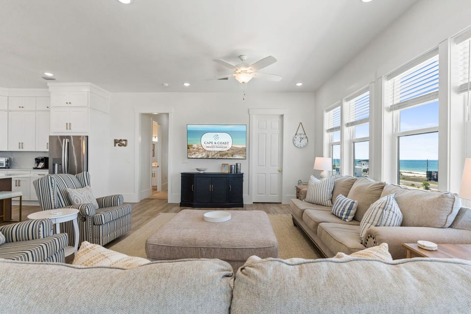 Sink into plush sofas while ocean views frame your getaway through floor-to-ceiling windows in this bright, beachy living space.