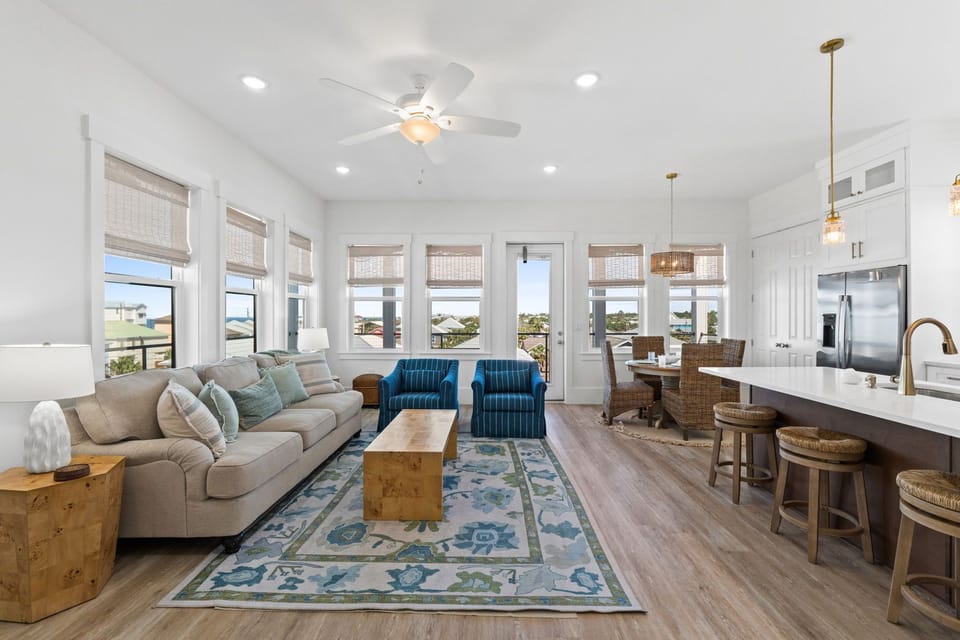 Relax in your bright, coastal-inspired living space with panoramic windows framing stunning views while you unwind on plush seating.
