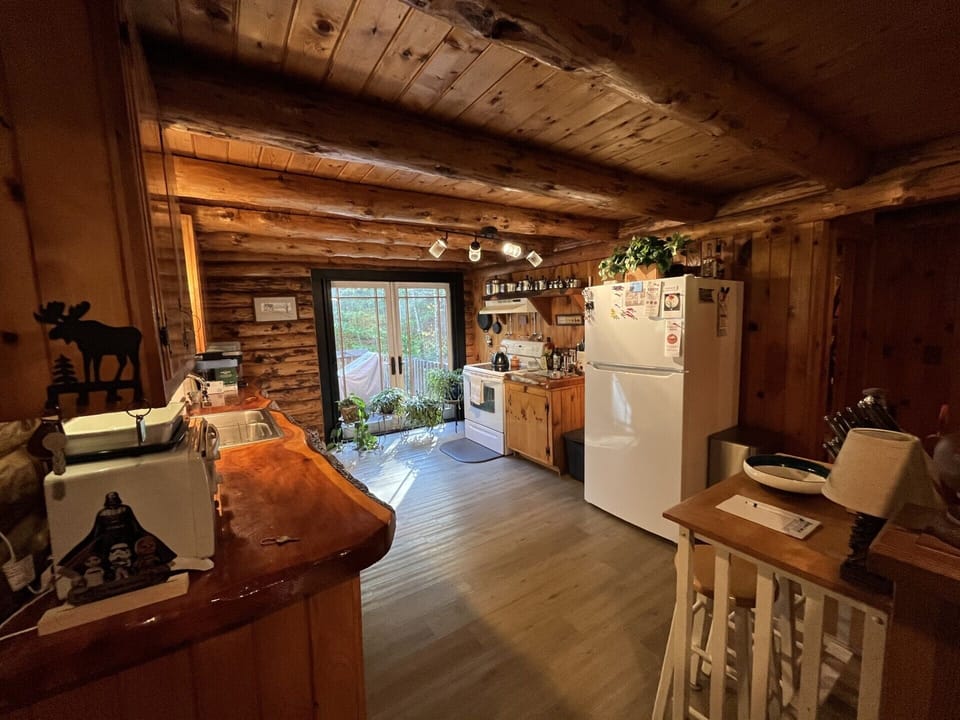 Step into your rustic cabin kitchen where exposed beams and warm wood create the perfect retreat atmosphere for cooking memorable meals.