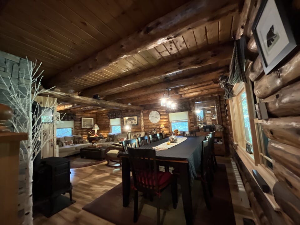 Gather around this rustic log cabin dining table where your group can share meals under authentic timber beams and warm lighting.