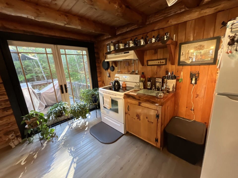 Your rustic cabin kitchen welcomes you with handcrafted wood cabinets, exposed beams, and garden views through French doors to your private deck.