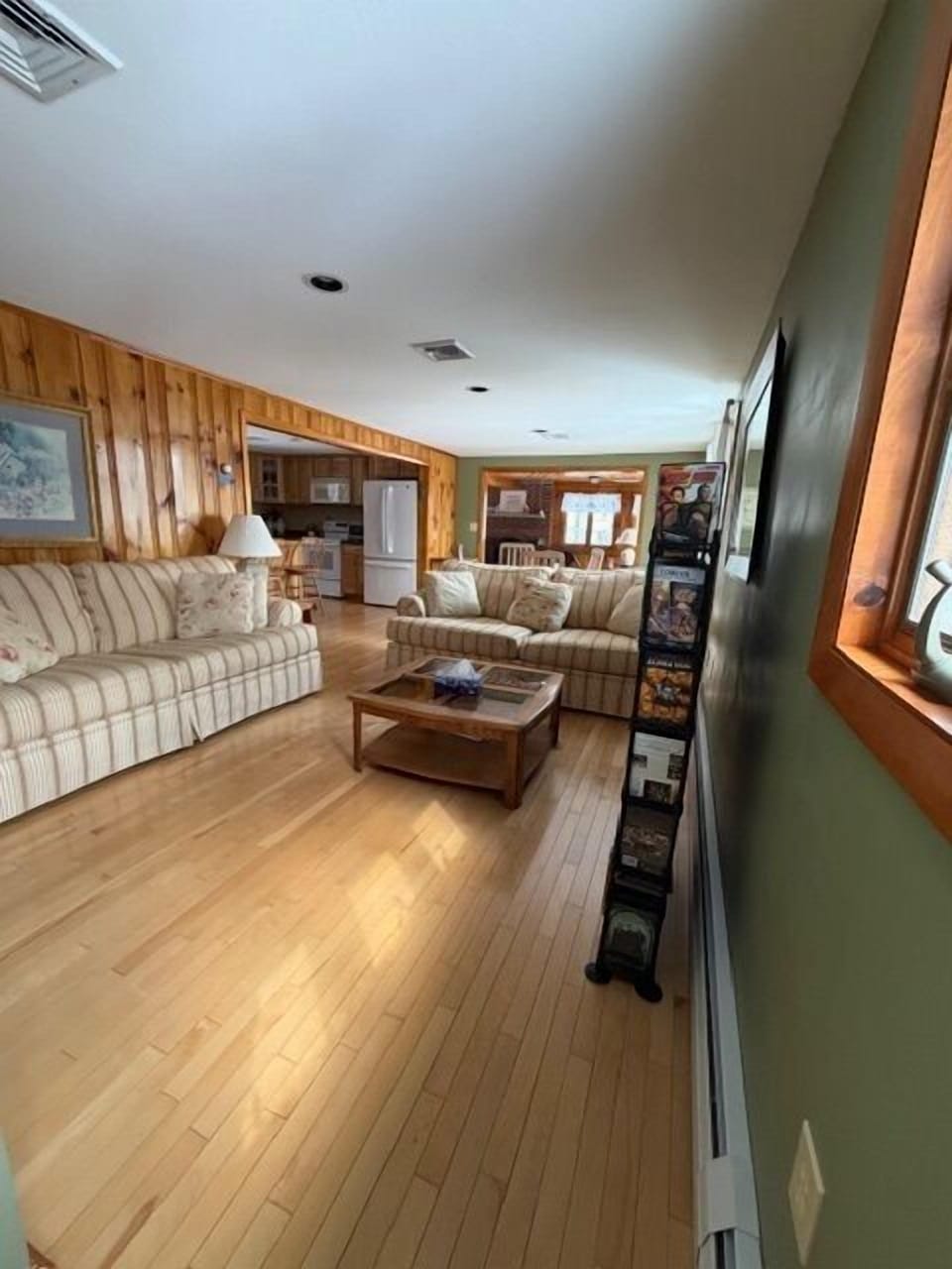 Unwind in your spacious living room with plush sofas and warm wood accents, flowing seamlessly into a fully equipped kitchen. Perfect for cozy evenings or gathering with loved ones in this welcoming retreat.