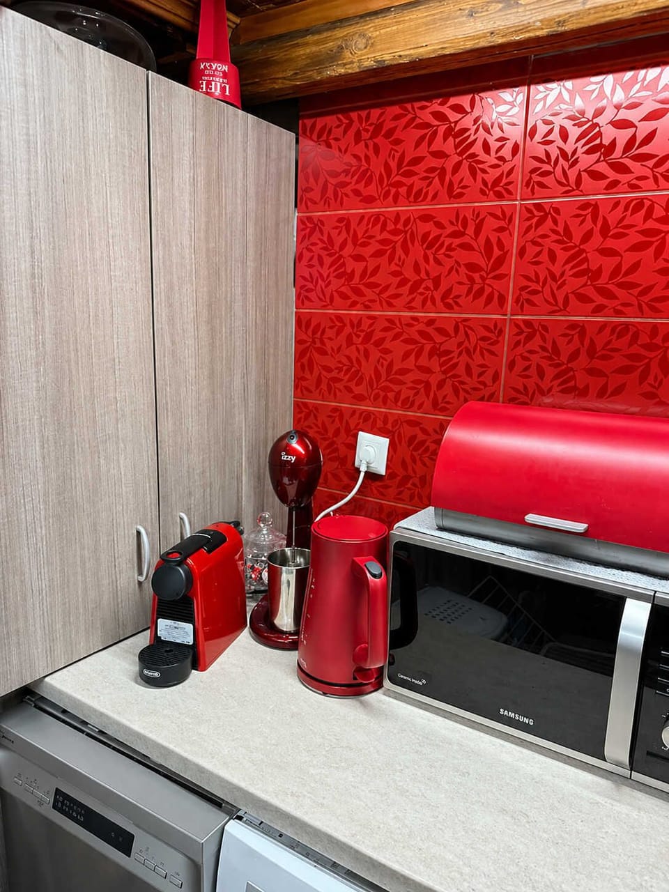 Modern kitchen corner with bold red accents and fully equipped appliances