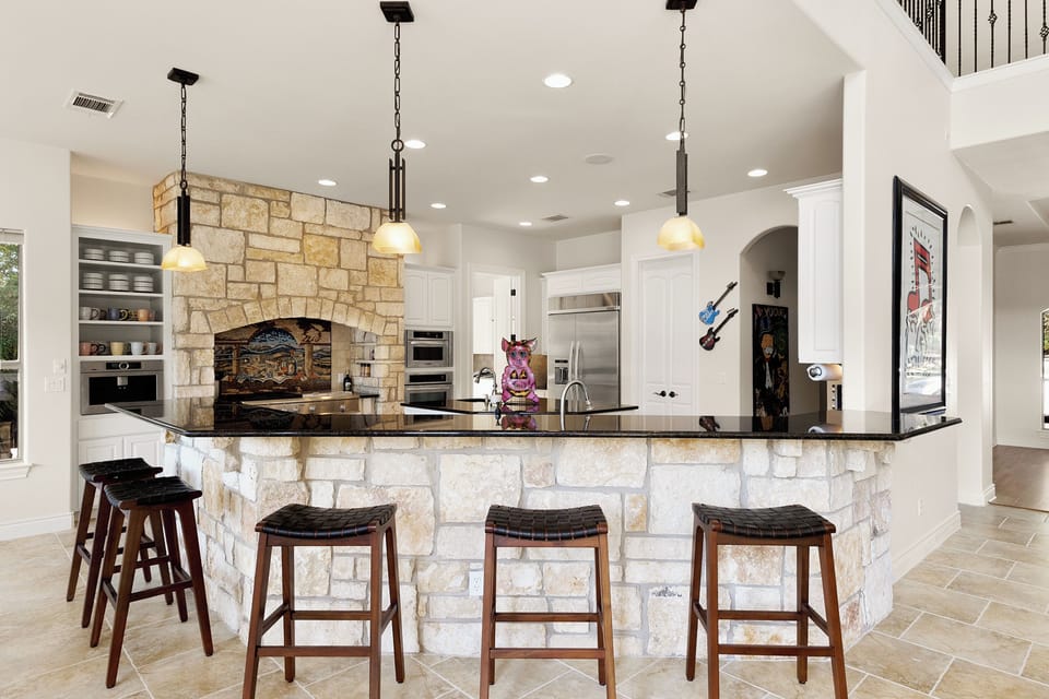 Stone kitchen island with bar seating and mosaic range hood