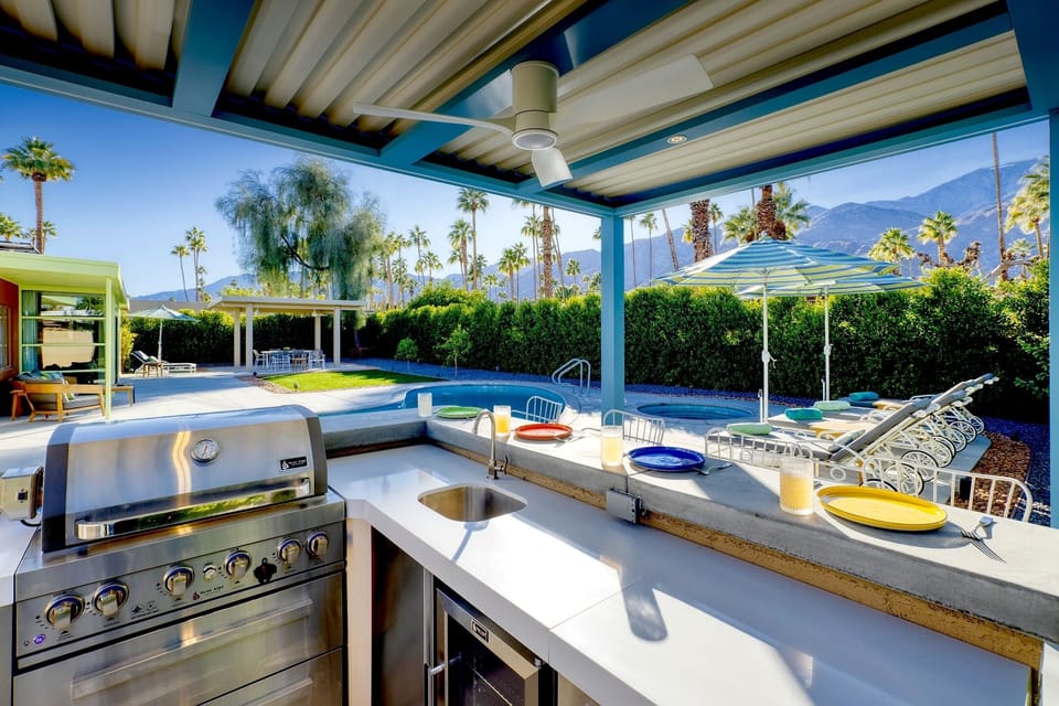 Outdoor kitchen with gas BBQ, sink, outdoor fridge, counter seating.  
