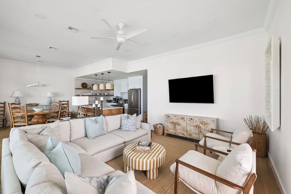 Sink into plush sofas in your bright, airy living space where coastal elegance meets modern comfort for perfect vacation relaxation.