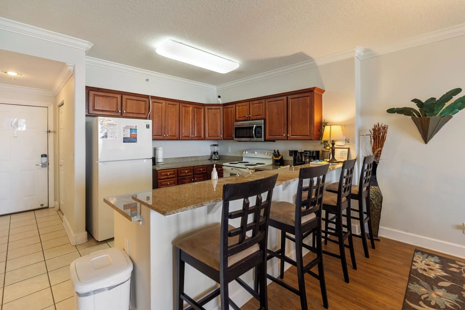 Your fully equipped kitchen features rich wood cabinets, granite countertops, and a breakfast bar where you can enjoy morning coffee or quick meals together.