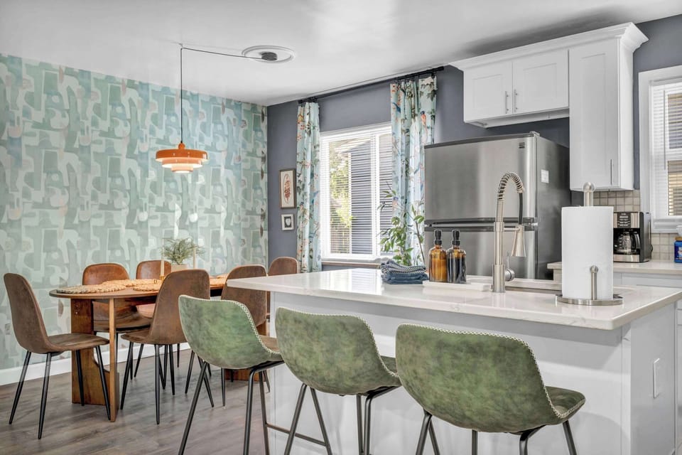 Dining room w/ green velvet chairs & pendant lighting — a stylish spot to gather over a meal.
