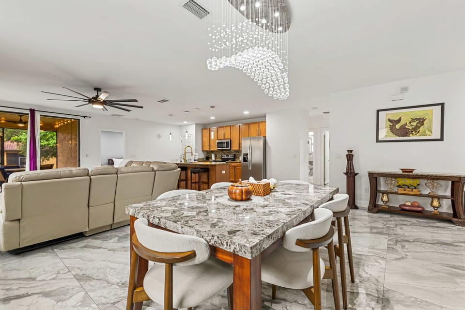 Open-concept dining & living area with marble floors & chandelier