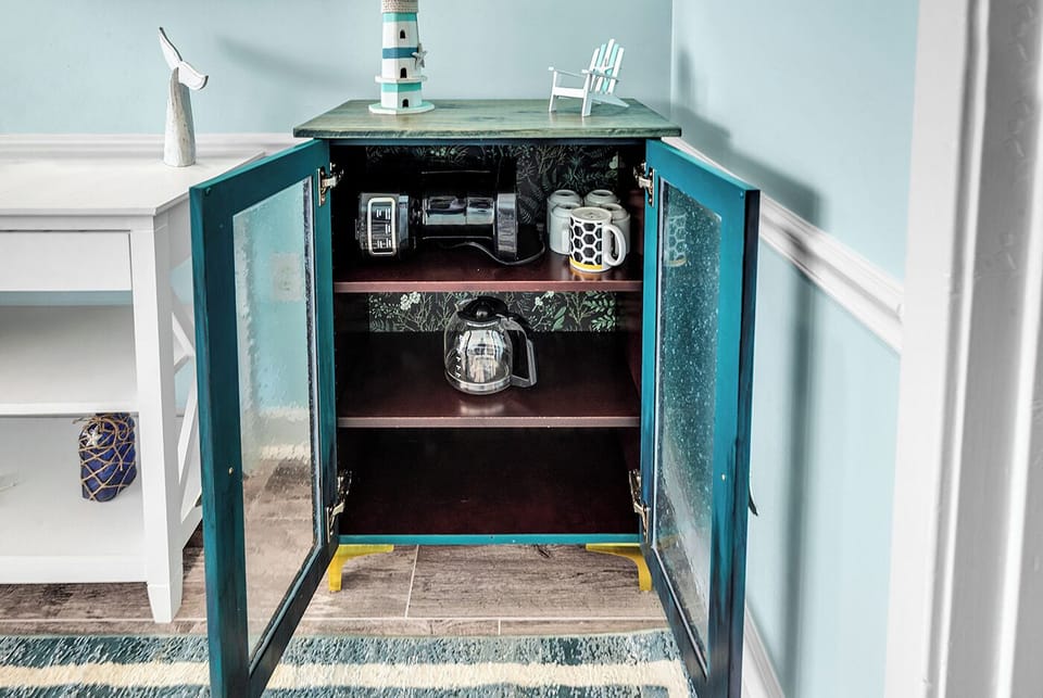 Speakeasy cabinet with coffee pot and mugs.