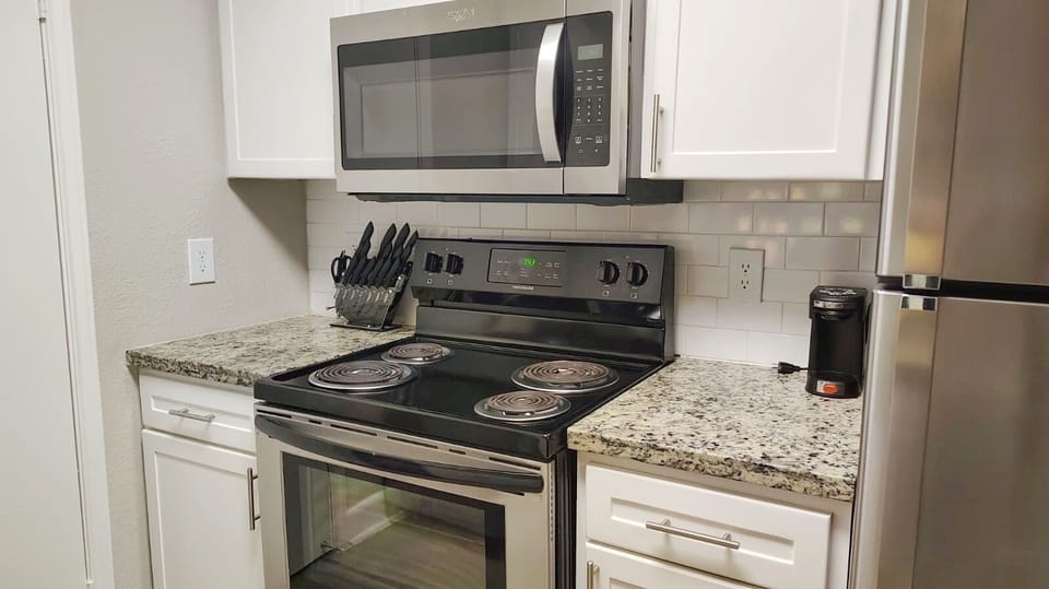 Modern kitchen with stainless appliances, granite counters, and coffee maker