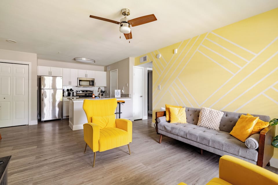 Bright, stylish living space with modern kitchen and bold yellow accents
